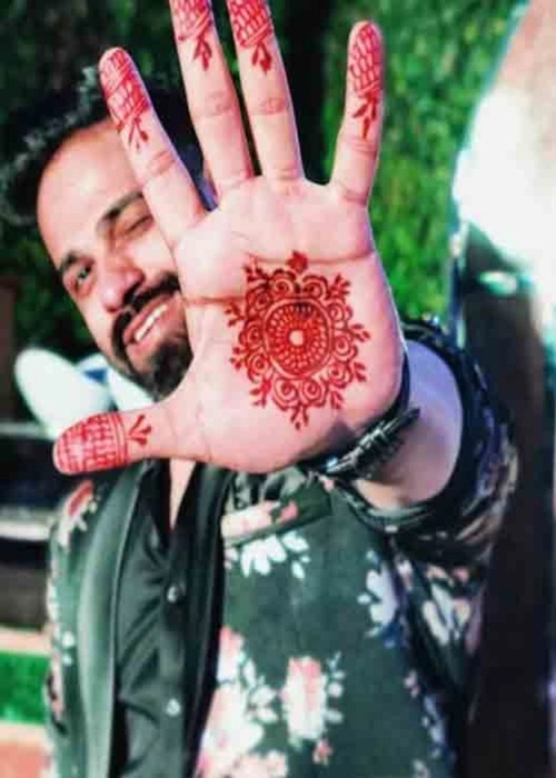 Photo of Intricate hand mehndi design with bride and groom portrait