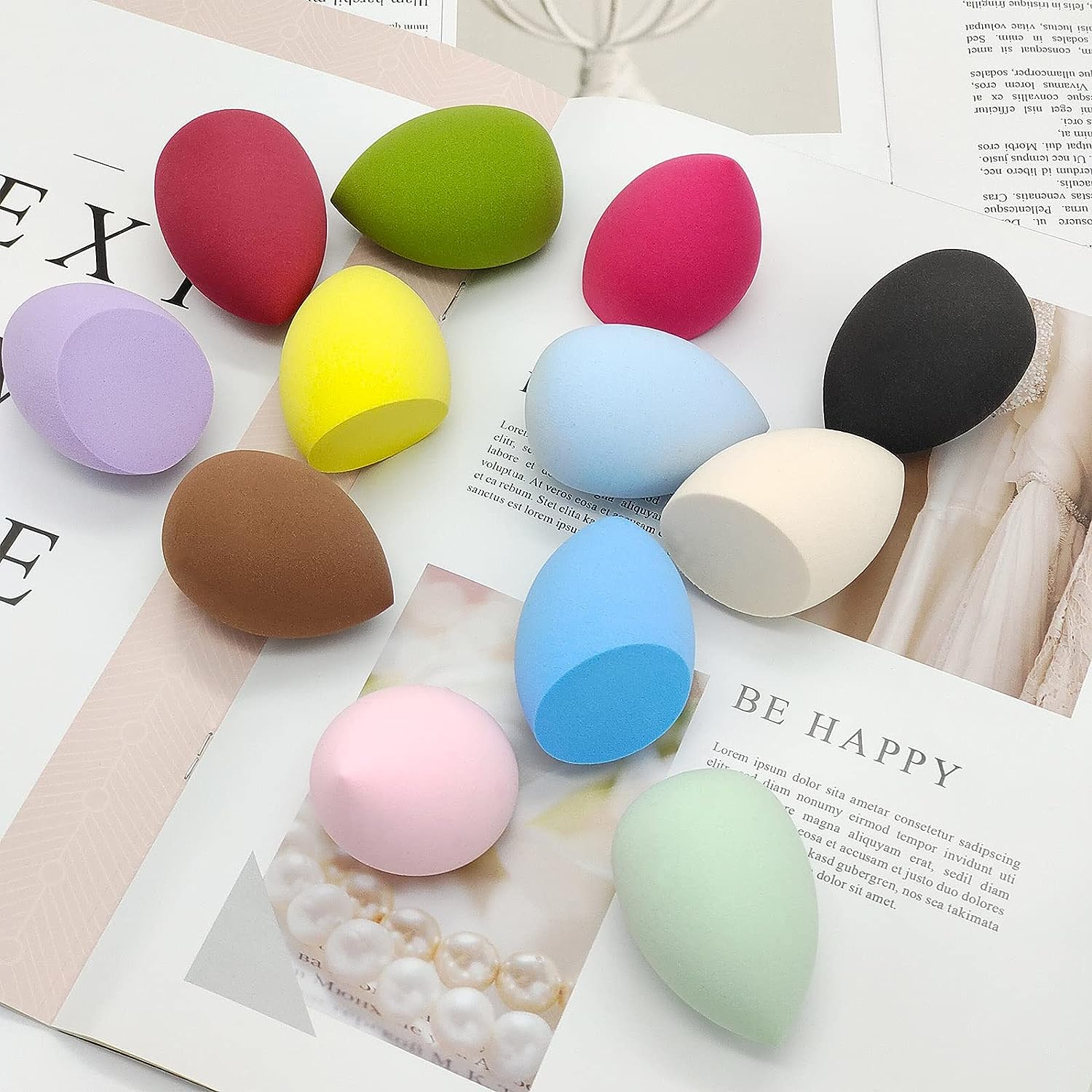 Makeup Sponges for cosmetics laying around on some papers. Multi colored, there shapes are irregular to reach to contours of the face.